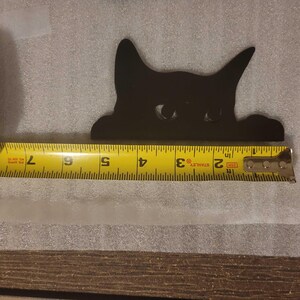 A photo showing the larger decorative cat with a tape measure. The width of the cat is about 5.25 inches.