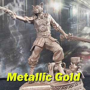 May include: A metallic gold figurine of a cat-like creature holding a pistol in one hand and a sword in the other. The figurine is standing on a decorative base with a teapot and a cup.