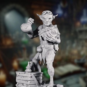 May include: A gray, detailed figurine of a goblin holding a flask and a round object. The goblin is wearing goggles and has a mischievous expression. The figurine is standing on a stack of books.