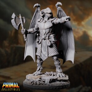 May include: A gray fantasy figurine of a dragon-like humanoid warrior, holding an axe and pointing. The figure has large wings, armor, and a detailed base. The "Primal Collectibles" logo is at the bottom.