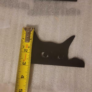 a photo with the decorative cat next to a tape measure. The tape measure shows the height of the cat at about 2.75 inches.