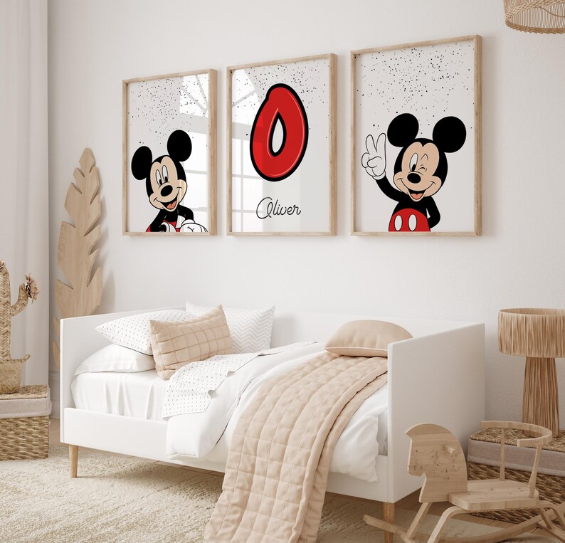 May include: Three framed prints featuring Mickey Mouse and a red number 0. One print shows Mickey Mouse smiling, another shows the number 0, and the third shows Mickey Mouse giving a peace sign. The prints are above a white bed with a beige comforter.