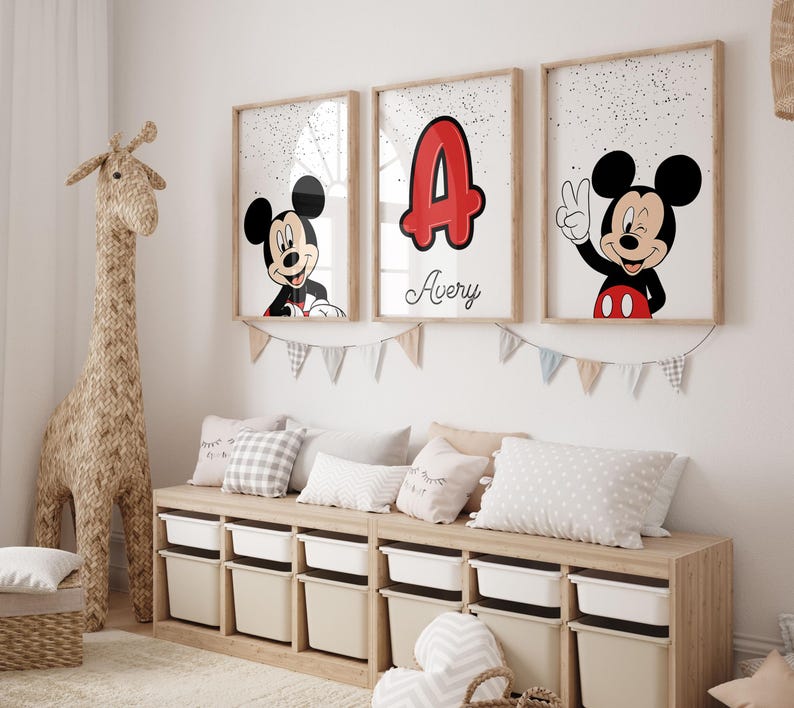 May include: Three framed Mickey Mouse art prints with a wooden frame. One features Mickey smiling, another shows the letter "A" in red with the name "Avery", and the third shows Mickey giving a peace sign. A woven giraffe and storage bench are also in the room.