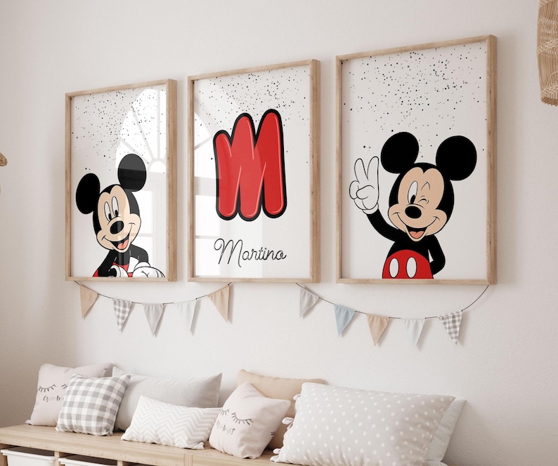 May include: Three framed prints featuring Mickey Mouse. One shows Mickey smiling, another displays a red letter "M" with the name "Martina", and the third has Mickey giving a peace sign. The prints are in light wood frames.