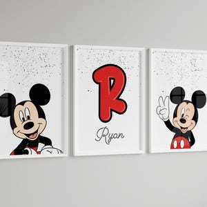 May include: Three framed prints featuring Mickey Mouse. One shows Mickey peeking over a surface, another displays a red letter "R" with the name "Ryan", and the third has Mickey giving a peace sign. All are set against a white background with black speckles.