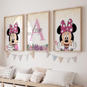 May include: Three framed prints with a gold glitter background. The center print features the letter "A" in pink with the name "Ariya" below it. The prints on either side feature a cartoon image of Minnie Mouse with a pink bow.