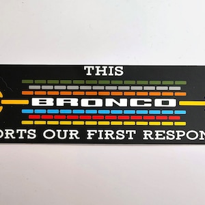 May include: Black and white sticker with the text "This Bronco Supports Our First Responders". The word "Bronco" is in a colorful, striped graphic.
