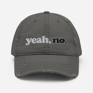 May include: Distressed gray baseball cap with the embroidered text "yeah, no." The hat has a pre-worn look with frayed edges and a curved brim. The text is in a combination of white and black.