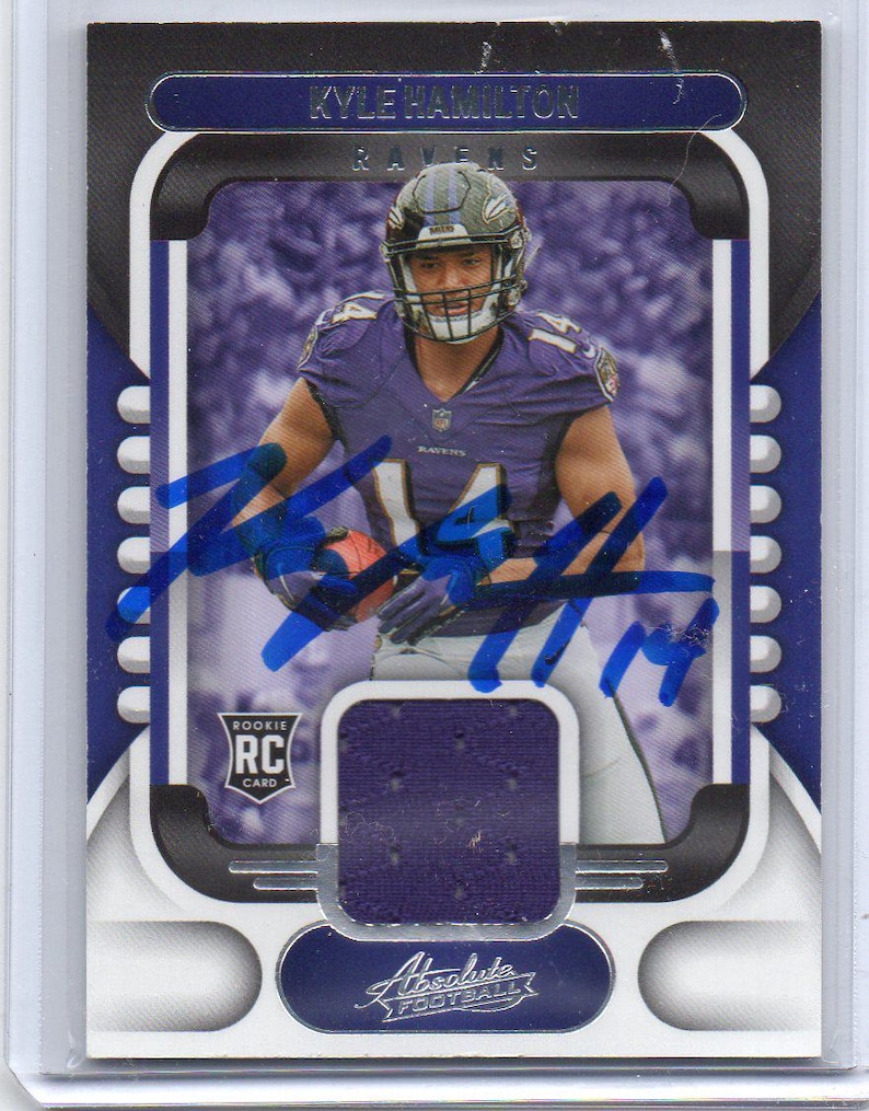 May include: A football trading card featuring Kyle Hamilton of the Ravens. The card has a photo of the player in his uniform, with the team name and player's name at the top. The card also includes a piece of the player's jersey and an autograph.