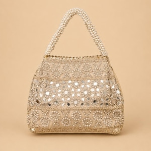 K&ouml;nnte beinhalten: Beige Handtasche mit Perlenhenkel. Die Tasche ist mit aufwendigen Blumenmustern, kleinen Spiegeln und perlenartigen Perlen verziert. Der Griff besteht aus eng aufgereihten wei&szlig;en Perlen.