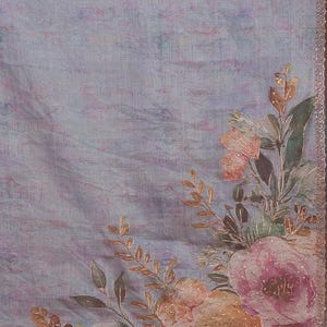May include: A light lavender fabric featuring a watercolor-style floral print in shades of peach, pink, and green. The design includes detailed roses and foliage with subtle gold accents and a decorative metallic trim along the straight edges.