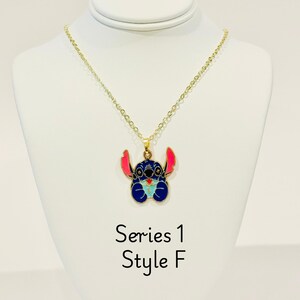 K&ouml;nnte beinhalten: Goldkette mit einem blauen Stitch-Charakter-Anh&auml;nger. Der Anh&auml;nger hat rosa Ohren und einen blauen K&ouml;rper mit einem hellblauen Herzen. Der Text "Series 1 Style F" befindet sich unter dem Anh&auml;nger.