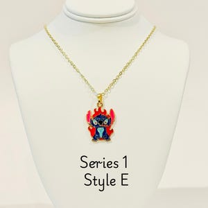 K&ouml;nnte beinhalten: Goldkette mit einem blauen und roten Emaille-Anh&auml;nger mit Stitch. Der Anh&auml;nger zeigt Stitch mit Flammen um ihn herum. Der Text "Series 1 Style E" ist unter dem Anh&auml;nger gedruckt.