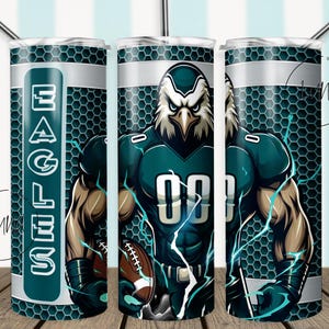 May include: A green and white tumbler with a football player wearing a green and white jersey with the word "Eagles" on the side. The player is holding a football and has a fierce expression on his face.