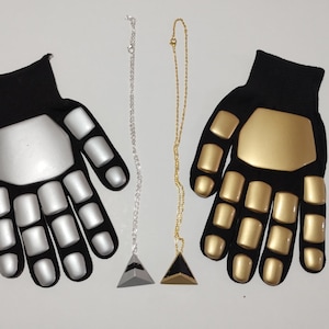 May include: Two black gloves with silver and gold padding on the fingers and palm. Each glove is paired with a matching pendant necklace, one silver and one gold.