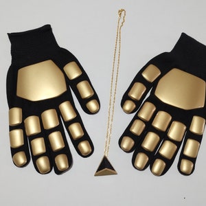 Puede incluir: Un par de guantes negros con nudillos acolchados dorados y un collar con un colgante triangular dorado.