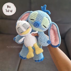 K&ouml;nnte beinhalten: Eine handgefertigte blaue Stitch-Puppe aus H&auml;kelarbeit umarmt eine wei&szlig;e und gelbe Donald Duck-Puppe aus H&auml;kelarbeit. Die Stitch-Puppe hat blaue, hellblaue und rosa Akzente. Die Donald Duck-Puppe hat wei&szlig;e, gelbe und graue Akzente. Die Worte "No Sew" stehen in einem Kreis oben links.