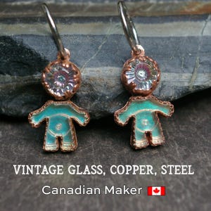 Peut inclure: Boucles d'oreilles faites à la main avec un design en cuivre et émail turquoise. Les boucles d'oreilles ont la forme de petites figurines avec une tête circulaire et un corps. Le texte "VINTAGE GLASS, COPPER, STEEL" est visible.