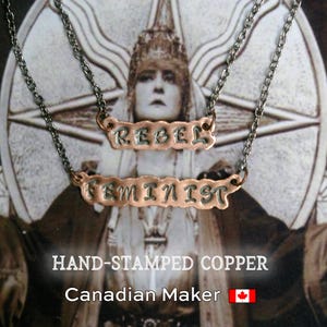 Peut inclure: Deux colliers en cuivre avec les mots "REBEL" et "FEMINIST" estampillés. Les colliers sont suspendus à une chaîne argentée. L'arrière-plan est une image vintage d'une femme. Le texte "HAND-STAMPED COPPER" et "Canadian Maker" sont également visibles.