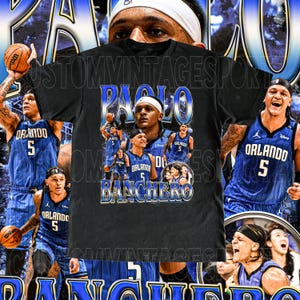 May include: Black t-shirt featuring a collage of images of Paolo Banchero, a basketball player, with the text "Paolo Banchero" in blue and white. The background includes images of Banchero in his Orlando Magic uniform.