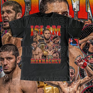 May include: Black t-shirt with a collage of images of a mixed martial arts fighter, including a close-up of the fighter's face, the text "ISLAM MAKHACHEV", and a UFC championship belt.