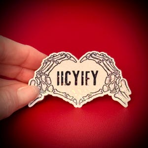 May include: A heart-shaped sticker with a skeleton hand design. The hands form the shape of a heart, with the word "HCYIFY" in the center. The sticker has a holographic, glittery finish and is set against a red background.