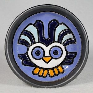 Puede incluir: Un plato de cerámica con un diseño de búho azul y blanco. El búho tiene ojos grandes y un pico amarillo. El plato está rodeado por un borde negro.