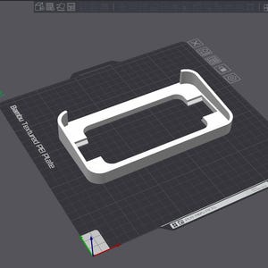 May include: A white plastic phone stand with a rectangular shape. The stand is designed to hold a phone upright. The stand is on a gray textured surface.