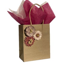 Piccola borsa regalo con fazzoletti e etichetta fatta a mano. Presenta fiori di carta color marrone, rosa e tortora. Confezione premurosa per piccoli regali e biglietti regalo.