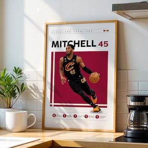 May include: A framed poster with a basketball player in a black and gold uniform, dribbling a basketball. The poster has the text "MITCHELL 45" in large white letters. The background is a maroon colour.