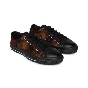 May include: A pair of black canvas low-top sneakers with a brown and orange abstract pattern. The shoes have white laces and a white stripe around the sole.
