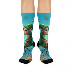 May include: A pair of knee-high socks with a whimsical fairy design. The socks feature a light blue background with illustrations of fairies, butterflies, and mushrooms. The fairies are depicted with green hair and dresses. The socks have black heels and toes.