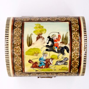 May include: A decorative wooden box with a curved lid. The box features a painted scene of figures on horseback, with a detailed mosaic border. The color palette includes shades of brown, beige, red, and blue, creating a vintage aesthetic.