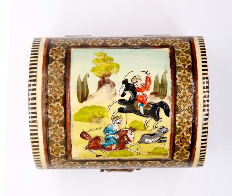 May include: A decorative wooden box with a curved lid. The box features a painted scene of figures on horseback, with a detailed mosaic border. The color palette includes shades of brown, beige, red, and blue, creating a vintage aesthetic.