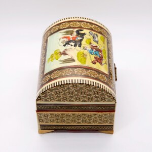 May include: A decorative, arched-top box with intricate mosaic and painted details. The box features a colorful scene on the curved lid, with figures and foliage. The box is approximately 6 inches long, 4 inches wide, and 4 inches tall.