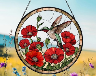 Op de afbeelding: Een hangend glas-in-loodraam met een kolibrie en rode klaprozen. De kolibrie is groen en heeft een lange snavel. De klaprozen zijn rood met groene bladeren. Het raam is rond en heeft een zwart frame.