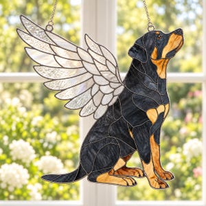 Könnte beinhalten: Ein Buntglas-Suncatcher, der einen Rottweiler mit großen, weißen, irisierenden Engelsflügeln darstellt. Der Hund ist schwarz-lohfarben, sitzt im Profil und schaut nach oben. Das Stück ist mit dunklen Metall-Lötlinien und einer Kette gefertigt.
