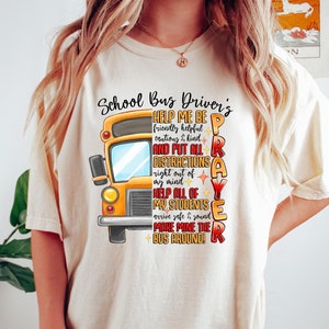 Puede incluir: Una camiseta blanca con un gráfico de autobús escolar amarillo y el texto "Oración del conductor del autobús escolar: Ayúdame a ser amable, servicial, prudente y amable y a eliminar todas las distracciones de mi mente. Ayuda a todos mis alumnos a llegar sanos y salvos. ¡Haz que mi autobús dé la vuelta!"