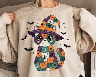 May include: Beige sweatshirt with a Halloween cat design. The cat wears a witch's hat and is made of patchwork squares in orange, purple, and teal. Bats and stars are scattered around the cat, creating a festive design.