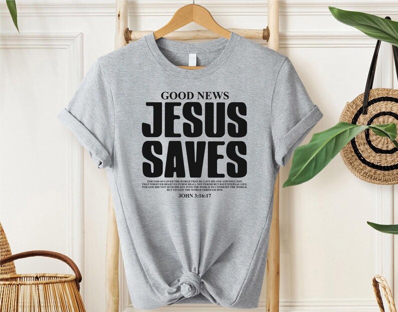May include: Gray t-shirt with the text "GOOD NEWS JESUS SAVES" in black. The shirt also includes a Bible verse from John 3:16-17.