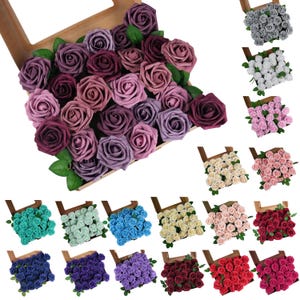May include: Assortment of artificial rose flower heads in various colours, including purple, pink, blue, green, white, red, and grey. The flowers are arranged in a wooden box.