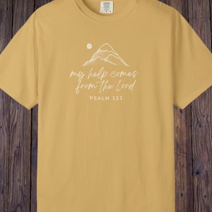 May include: Mustard yellow t-shirt featuring a white mountain graphic and the text "my help comes from the Lord" and "PSALM 121". The shirt is made of a soft, comfortable material.