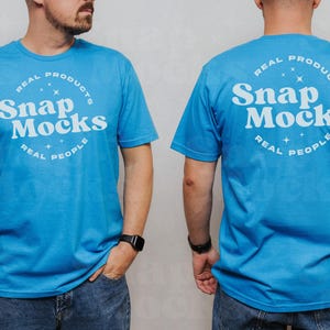 Op de afbeelding: Een blauw t-shirt met een witte cirkelvormige afbeelding met de tekst "Real Products Snap Mocks Real People".