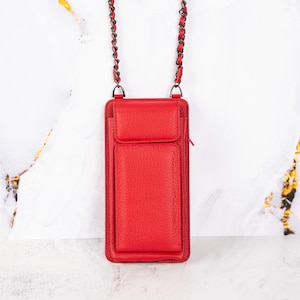 May include: A red leather crossbody phone bag with a chain strap. The bag has a flap closure and a zippered pocket on the front.