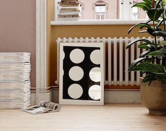 May include: A white framed print with a black background and five white circles arranged vertically. The print is hanging on a wall next to a white radiator.