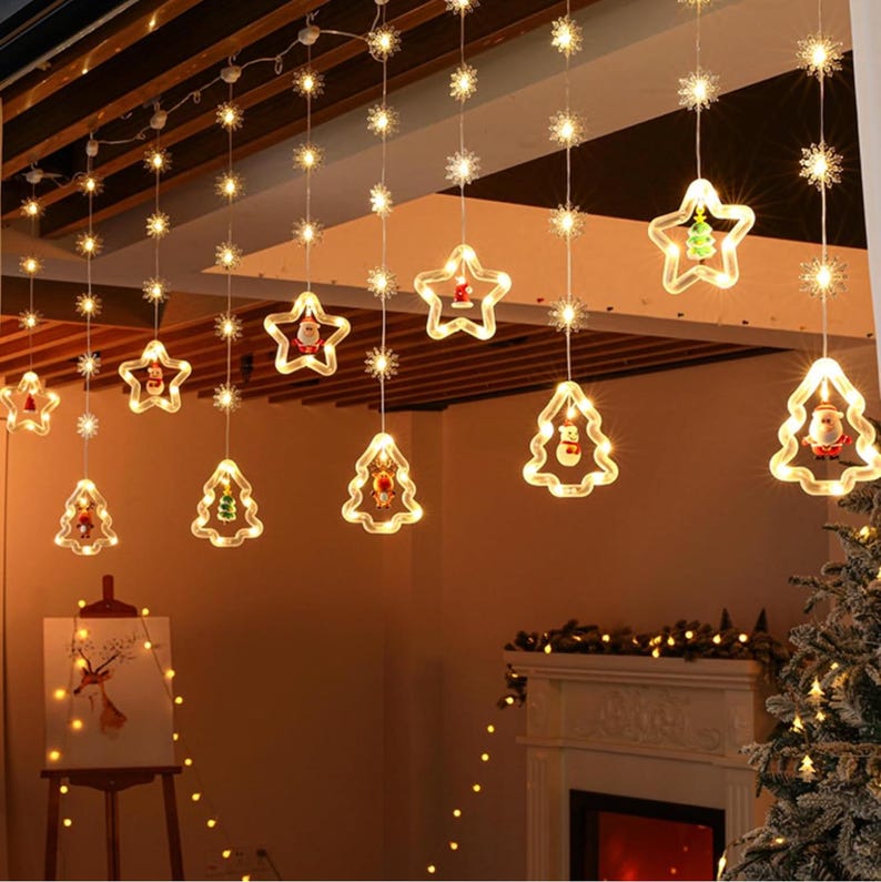 May include: A string of Christmas lights with clear bulbs and snowflake and star-shaped cutouts. The lights are strung across a ceiling and have small, colorful figures inside the cutouts. The lights are on and illuminating the room.