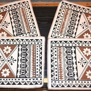 May include: Four rectangular placemats with a geometric design. The placemats have a cream background with brown, black, and white patterns. The design includes triangles, floral motifs, and linear elements.