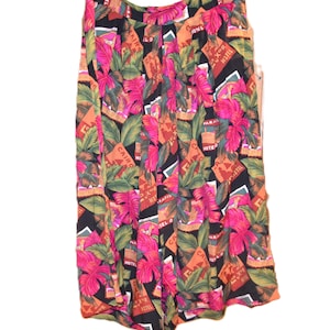 Puede incluir: Falda vintage con un estampado tropical vibrante. La falda presenta un fondo negro con ilustraciones coloridas de flores rosas, hojas verdes y letreros de hoteles naranjas. La falda tiene un diseño plisado y una cintura alta.