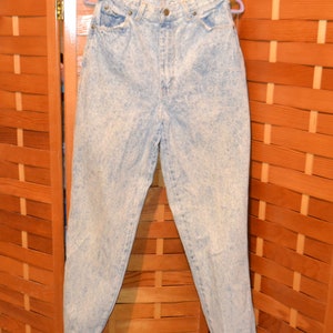 May include: Light blue acid wash denim jeans with a high waist and a relaxed fit.