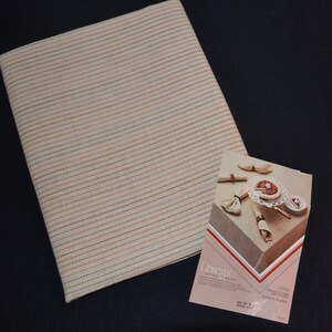 May include: A beige and brown striped tablecloth with a small advertisement for Donegal linen tablecloth. The advertisement shows a table setting with a pie and napkins.